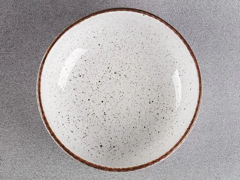 White empty deep clay plate with a spoon on a gray background. Stock Photos