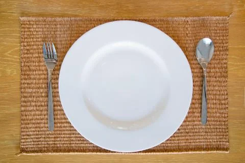 White empty dish with spoon and fork set on thai mat wooden desk Foto stock