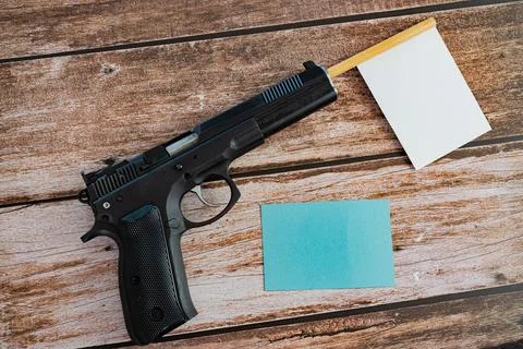 White empty flag sticking out of black pistol barrel and blue empty note on  Stock Photos