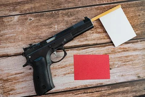 White empty flag sticking out of black pistol barrel and red empty note on w Stock Photos