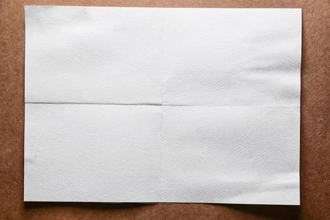 White empty folded sheet of paper on a brown paper background Stock Photos