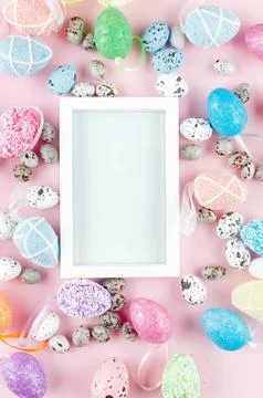 White empty frame with colored eggs around on pink Stock Photos