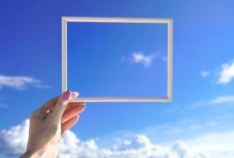 White empty horizontal frame in female hand against blue sky. Space for your Фото