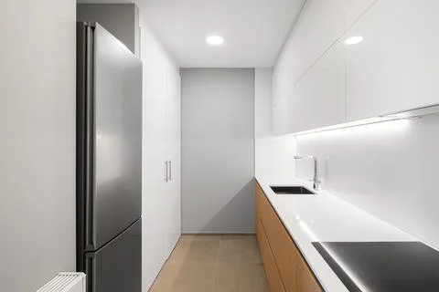 White empty modern kitchen with fridge, stove and sink Фото