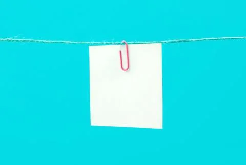 White empty paper sheet on the string with paperclip against blue background Stock Photos