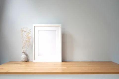 White empty picture frame and potted plant on wooden table. Foto stock