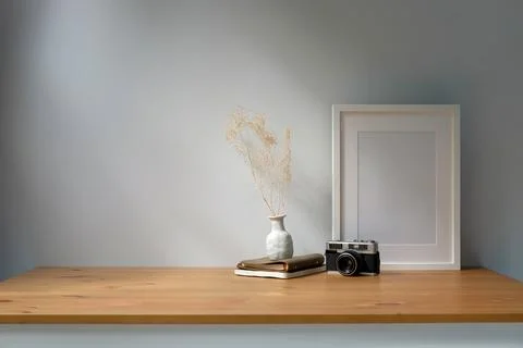 White empty picture frame, retro camera and potted plant on wooden table. Stock Photos