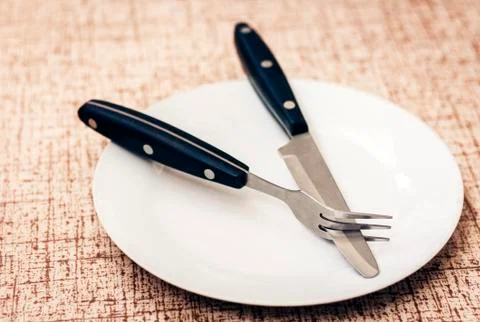 White empty plate with knife and fork on wooden background . Stock Photos