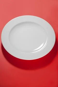 White empty plate ping -red background with shadow Stock Photos