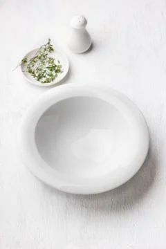 White empty plate, salt shaker, plate with greens on light gray background Stock-Fotos