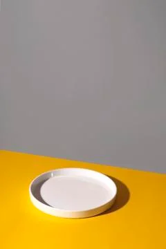 White empty plate on a yellow background. Stock Photos