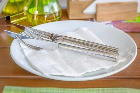 White empty plates with fork and knife on a wooden table Stock Photos