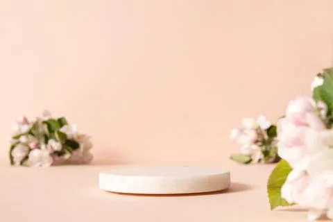 White empty podium and blurred cherry blossom flowers against pink background Stock Photos