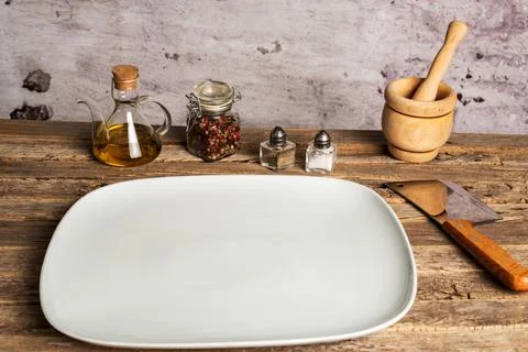 White empty rectangular plate next to salt, pepper, oil and a mortar on an .. Stock Photos