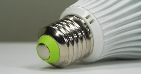 White energy saving LED lamp with E27 base on grey background, zoom-out video Stock Footage 333574728