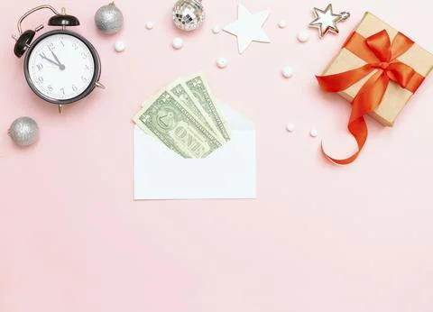White envelope with dollars on a pink background, New Year's clock, gift. Фото