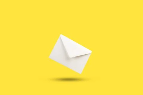 A white envelope floating on a yellow background Stock Photos