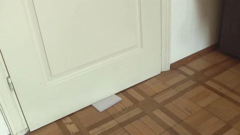 White envelope with message slipped under  door. Stock Footage 71679595