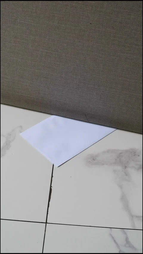 A white envelope with a message slipped under a door on a marble floor Stock Footage 330480763