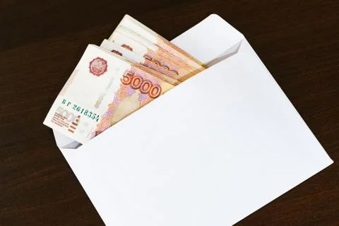 A white envelope with a pack of Russian five thousand ruble banknotes lies on Stock Photos