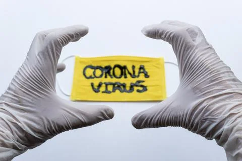 White Esterilized gloves making an angry hand expression over yellow face mask 스톡 사진