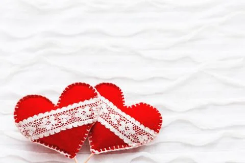 White fabric background with ruche.Two felt hearts with laces, symbol of love Stock Photos