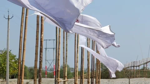 White fabric flags fluttering on bamboo poles in open outdoor setting Stock Footage 331276837