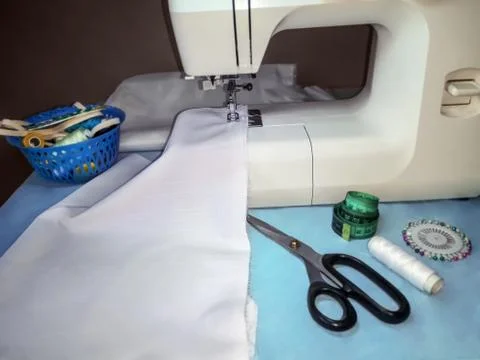 White fabric inserted in a sewing machine and sewing materials around Foto stock