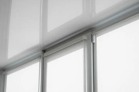 White fabric roller blinds on the plastic window on a balcony in the living room Stock Photos