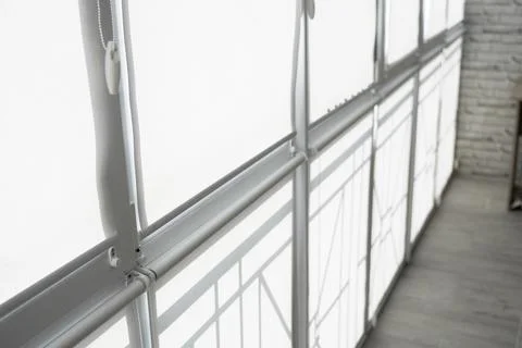 White fabric roller blinds on the plastic window on a balcony in the living room Stock Photos