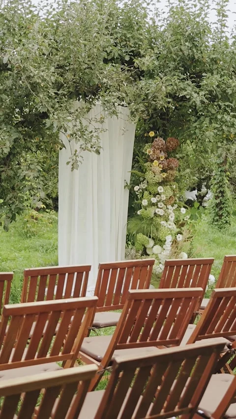 White fabric wedding arch on a tree and charming wooden chairs and a stunning Stock Footage 306622941