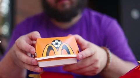 White fat man with beard holds, twists and turns box with Big Mac burger Stock Footage 340428097
