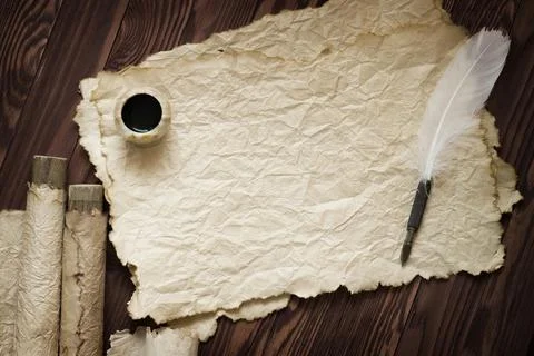 White feather and ancient scroll on brown plank Stock Photos