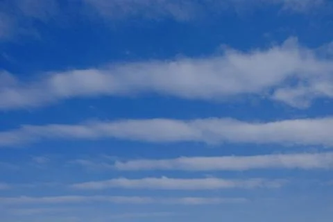 White feather clouds against the blue sky. Striped sky. Background. Stock Photos