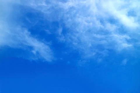 White feathery clouds spread on vibrant blue sky Stock Photos