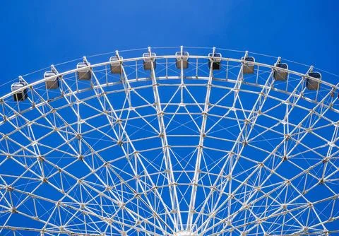 White Ferris wheel on background a clear blue sky in amusement park at fair in Stock Photos