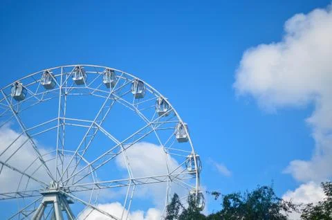 White ferris wheel carousel on a background of blue blue sky with white cloud Stock Photos