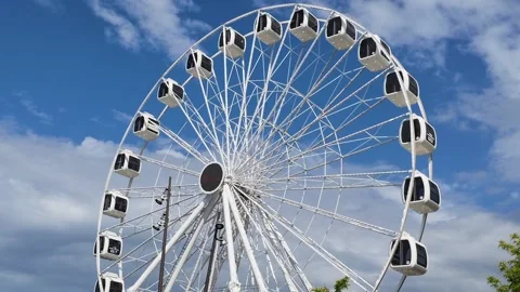 White ferris wheel rotates against clean blue sky Stock Footage 336448178