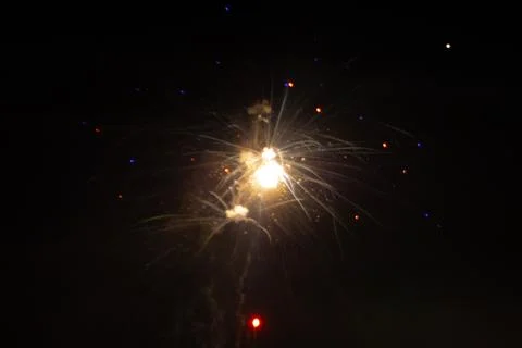 A white firework explodes in the center of the night sky, sending soft streaks. Stock Photos