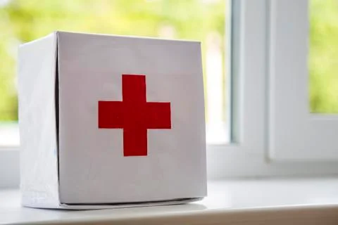 White first aid kit with red cross indoors on windowsill on blurred backgroun 写真素材