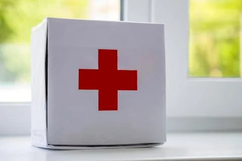 White first aid kit with red cross indoors on windowsill on blurred backgroun 写真素材