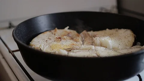 White fish fried in a pan on the stove. Side view. Nice plan Stock Footage 108944482