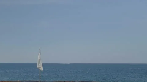 White flag swaying with ocean background Stock Footage 169475111