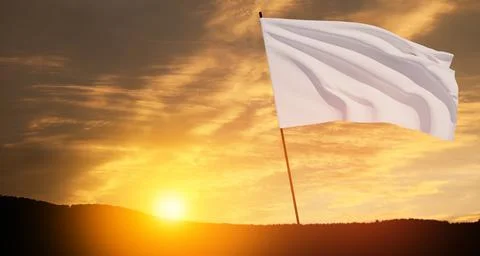 White flag waving in the wind on flagpole against the sunset sky with clouds. Stock Photos