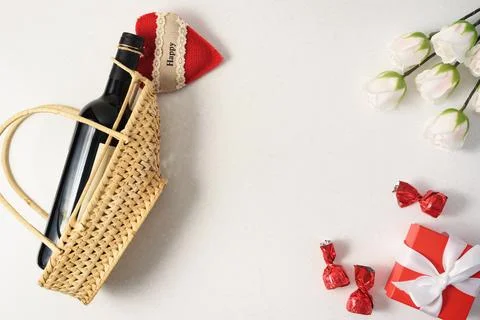 White flat lay with wine bottle, red gift box, sweets and flowers, copyspace Stock Photos