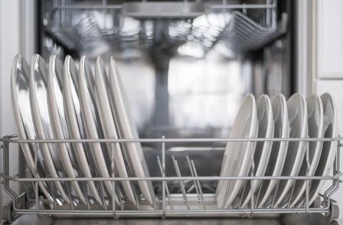 White flat plates are loaded into the dishwasher Stock Photos