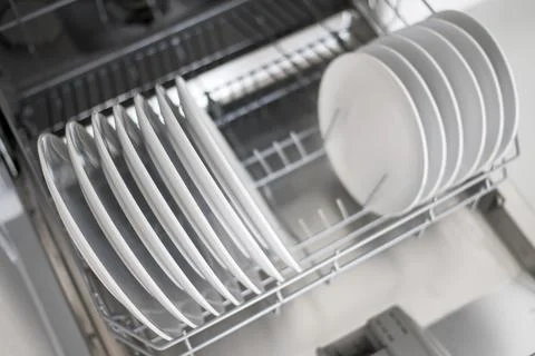 White flat plates are loaded into the dishwasher Stock Photos