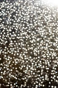 White flecks of defocused light creates a snowfall like bokeh effect in brigh Stock Photos