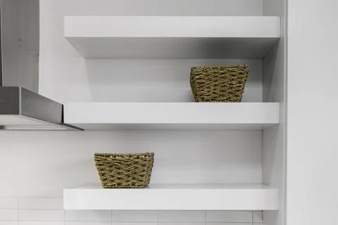 White Floating Shelves In Modern Kitchen With Wicker Baskets For Storage. Stock Photos
