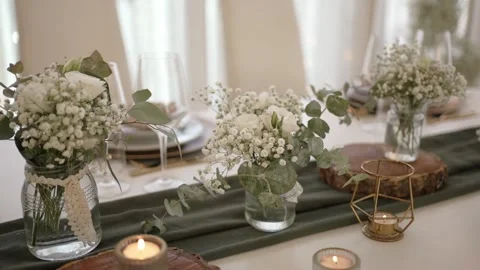 White floral table decor with baby’s breath and candlelight on rustic runner Stock Footage 312208051